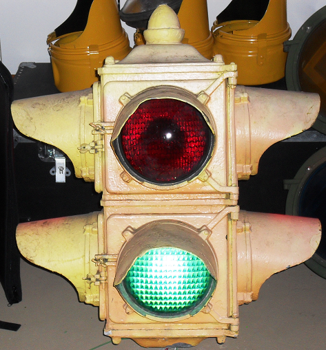 New York City Ruleta traffic signal
About three weeks ago, I purchased this very rare 1920s to 1930s Ruleta two-section, fixed four-way traffic signal. Had originally seen service in the city of New York, and it was used in a scene from the 1950 movie called "Cinderella Man."

Was removed from service in the mid to late 1970s. Is in the same condition as it was when it was removed from service. Will remain that way.

From the 1920s until the early 1940s or so, Ruleta traffic signals, like this one, were installed throughout the entire of city of New York. It was not until the mid 1940s that Marbelite took over Ruleta. The company's earliest signals depicted the same designs and features to that of Ruleta's designs and features. 

Because this traffic signal did not have a yellow indication, two sequences were originally used for the transition from green to red. Prior to 1952, there was a dark-out period that had lasted for only a handful of seconds when a Ruleta traffic signal changed from green to red. After 1952, the red indication had overlapped the green indication. As a result, both indications were lit at the same time.  

Because the original requirement in New York City was red and green indications for all traffic signals, Ruleta traffic signals there had operated in both sequences.  

By the 1960s, many Ruleta traffic signals were removed and replaced by modern (at that time) traffic signals, like two-section (red and green as well) Marbelite traffic signals. 

They existed in service until the very late 1980s. Today, Ruleta traffic signals are extinct. 
Keywords: Traffic_Lights