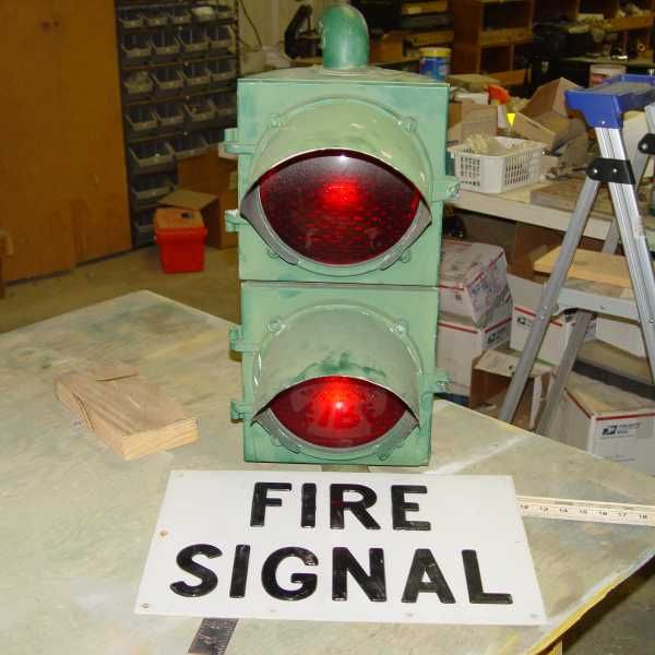 Econolite "Long Groove" Fire Signal
This was the first signal I ever installed.  It was a fire signal at the intersection of Moraga Rd. and Orchard Rd. in Orinda, CA.  It was a blind entrance for fire engines entering from the fire station on the corner.  The original signal was span wired over the center of the intersection and had two heads facing opposite directions down the arterial street.  It hung next to an illuminated sign box.  When the station received a call, the signal would flash over and under (bouncing beacon) and the sign would light up.  The station was replaced after I retired and the crew DROPPED the signal when they took it down.  Unbeknownst to me someone saved the side that wasn't badly damaged and saved one of the signs from the sign box.  I happened to run across that person unexpectedly who said, "I have something for you."

I'll build a new single sided sign box (I still have spare ballasts and starters for the F18T12WW lamps we used in the sign box) so the surviving half of the signal and sign should light up as it once did.
Keywords: Traffic_Lights