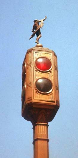 "Bronze Signal"
The "Bronze Signal" was an ornamental traffic signal that was in use in New York City in the 20th century. Designed by Joseph Freedlander and manufactured by General Electric, the head had four sides, and red and green signal indications were in use. It was first unveiled in 1929 in Manhattan, and approximately 104 were in service on one segment of 5th Av. Each traffic signal had a statuette on the top, which depicted the Roman god Mercury. Until the 1960s, all 104 heads were still in operation. Before 1970, all heads were replaced by modern three-section traffic signals. In spite of this, a handful of the original Mercury statuettes were saved in the removal process, and those survivors remain in existence to this day.
Keywords: Traffic_Lights