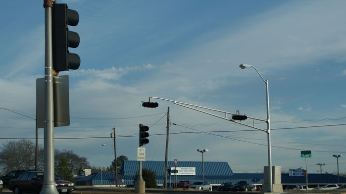 Truss Arm Signals with Surrounding Signals and Form 400 in Background
Older Intersection with Truss Arm Signal Masts and signals on shorter poles in the median of both the main street and the other main road.

Look Closely and you can see a Form 400 in the Background.
Keywords: Traffic_Lights