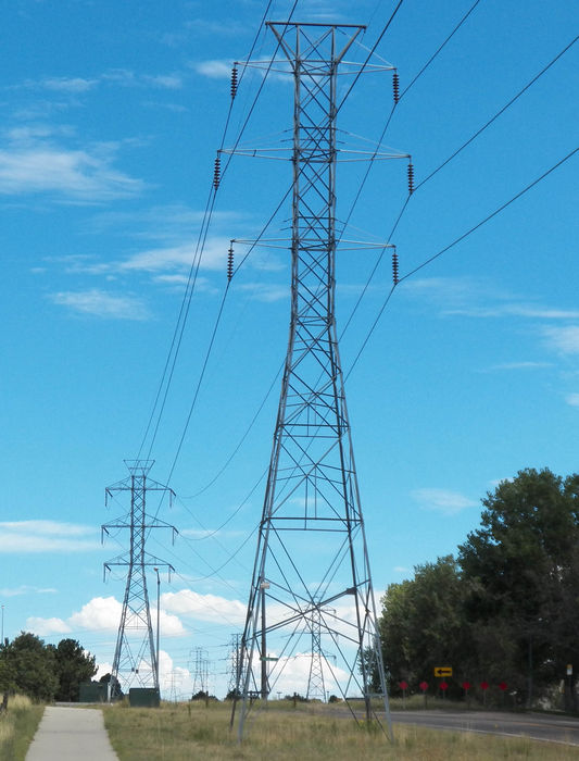 Dual 230 kV circuit towers.
Before you say anything, the tower in the foreground (closest to me) has fiberglass brackets, so because fiberglass is an insulator, (Though not as good of an insulator as porcelain or polymer) it halves the amount of disc insulators needed if it was connected to straight metal.

As you see in the background the tower is much bigger and has more disc insulators used because the brackets are metal.

I think they did this for the regular suspension straight towers because it is cheaper. For one, fiberglass is cheaper then metal, and since fiberglass is an insulator, you need only half as many disc insulators. But the overall cost is that these don't last as long as if you used the bigger towers.

The tower here is the last "cheap" tower heading east and east of here on this dual-circuit the straight suspension towers are all metal and have 16 disc insulators instead of 8. And are much bigger.

Though these towers are still old, they still decided to be cheaper here, but at least they still used lattice towers instead of wooden poles.
Keywords: Miscellaneous