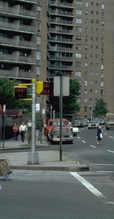 Vintage N.Y.C. pedestrian signals
This pair was once located at the corner of Queens Blvd. in Queens, New York. Circa 1971. Two different kinds are in the photograph. The one that faces you is a Marbelite model LPS-20 incandescent pedestrian signal, while the one next to it is a bulky neon pedestrian signal from Winko-Matic. 

The bulky neon pedestrian signal from Winko-Matic was first introduced in New York City in 1955, and it was installed on New York City streets from the time of its debut until the early 1970s. An interesting set-up, in which was common to see on many major thoroughfares throughout New York City was what is shown above. A Marbelite LPS-20 faced the crosswalk of a major thoroughfare, while a Winko-Matic neon pedestrian signal was positioned to face the crosswalk of a cross street. 

Sometimes, both kinds were installed at the same time, while one was first installed before the other. In this case, that would be the Winko-Matic neon pedestrian signal. A crosswalk for the main drag lacked actual pedestrian signals; however, vehicular heads were typically in use. One for each direction of the main drag. Uniformity is a likely reason for the addition of new pedestrian signals in later years at existing signalized intersections.

This is just one of many interesting and old N.Y.C. signal arrangements at intersections, in which are practically no longer in existence today.
Keywords: Traffic_Lights