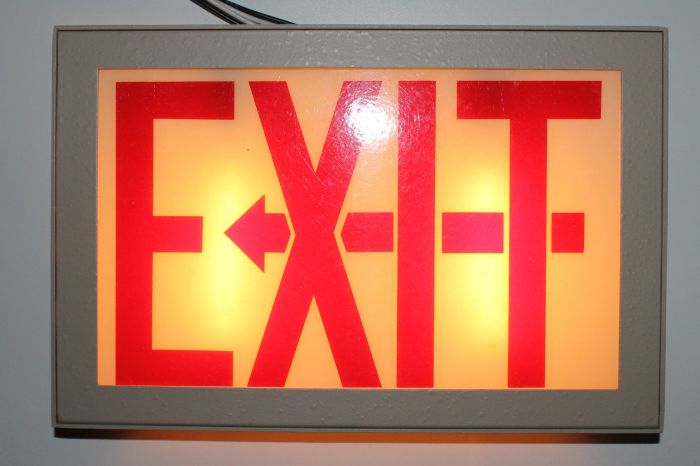Prescolite Exit Sign
eBay find, it's NOS but missing the backplate. I do have the orignal sales receipt from 1981 though lol. 

this has a open style faceplate where the background of the sign is also illuminated. Chicago has a requirement to use similar styled exit signs. Anyway, I don't think this style saw use here in Ontario. This one is incandescent but I think fluorescents might look better in this style sign. You can't can't use standard exit sign LED retrofits in them too, the red light will reduce the visibility. A white LED retrofit kit designed for Chicago exit signs or the running man style signs would work. For display purposes a candelabra LED in a bayonet adapter will also work.   
Keywords: Misc_Fixtures