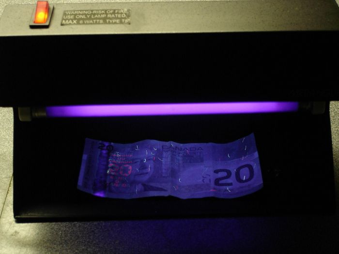 Merangue Counterfeit Currency Detector 
Here is the Merangue deluxe counterfeit currency detector lit showing the UV features in an older Canadian $20 bill,you can see the red/blue Bank OF Canada UV feature as well as the embedded fibers that glow.
Keywords: Misc_Fixtures