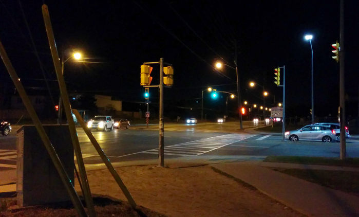 Competing Factions 
At the Markham-Toronto border the streetlights transition from LED to HPS. Note the Markham owned LED on the cross street, while the street I'm facing down is owned by Toronto which is still HPS.  
Keywords: Lit_Lighting
