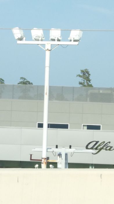 Four Metal Halide flood light fixtures below the LED parking lot light fixtures
I believe the metal halide are disconnected, due to the fact theres LED parking lot light fixtures there.

This is at a car lot. Also I was in the car in the passenger seat.
Keywords: Misc_Fixtures