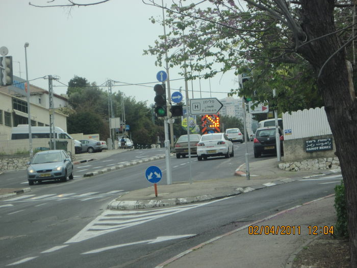 The portable "Lane blocked", when the left lane in this road was blocked
It is in Ramot Remez neighborhood, Haifa.
I photographed such that the arrow would appear in this picture, since it is flashing.
The two large upper circular LEDs arrays, strobes before the arrow appears for 1/2 secs and then goes out.
It is designed to be carried by a pickup truck, but i don't know if the pickup is there.
This LED sign, can show rightdown and leftdown arrows and X, by its circular LEDs arrays.
Keywords: Traffic_Lights