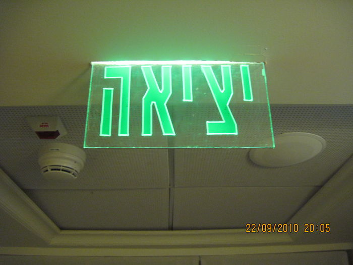 A fluorescent edge lit Exit sign in the corridor of the tenements of my Grandma's protected accommodation, Pisgat Hen
It is lit by a single regualr daylight F8T5. And the lamp can get its power, both by the preheat magnetic ballast, and by the emergency inverter that feed from a 12V NiCd battery in case of power interruption.
Keywords: Misc_Fixtures