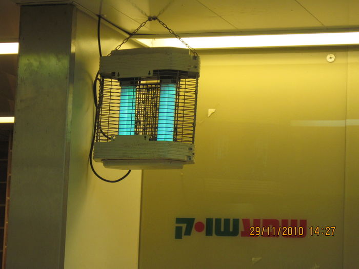 A bug-zapper inside "Shefa Shook" supermarket in Kiryat Ata
It have two U shaped actinic UVA (Please read the note carefully) fluorescent lamps.
The light isn't that green as in this pictures, but rather the regular pale blue color of these type of lamps.
Note: Calling the Actinic UVA lamps that used for bug-zappers "Blacklights" (As they are used to be called such in the US) is very wrong, since these lamps aren't designed to cause blacklight effects. The true "Blacklights" have a wood glass in addition to the actinic UVA phosphor.
Keywords: Misc_Fixtures