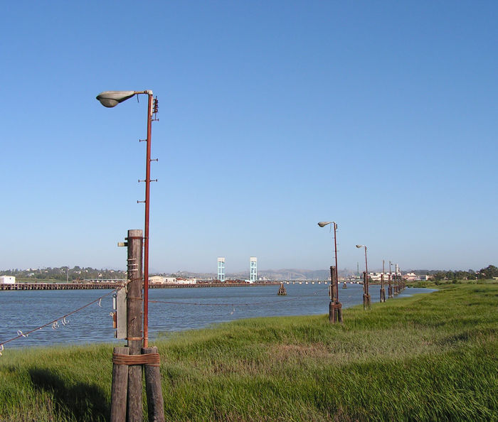 Difficult to service, but it didn't deter wire thieves
On Mare Island by the bay in Northern California, these long out-of-use M400's are located in a swampy area that cannot be walked on. Yet, someone managed to remove the wiring from each & every one of these.
Keywords: American_Streetlights