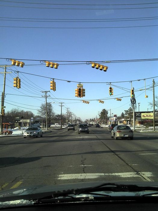 My neck of the woods
I did not take this picture.

This is 21 Mile and Van Dyke Ave. in Shelby Twp, MI. Upgrading. The original signals are Eagle with Dialight Red LED and incandescent everything else, running on a four-phase pretimed EPIC140 controller. The new signals use dual ring phasing and FYA Lefts, and all GE GT1 LEDs. New setup is vehicle and pedestrian actuated, coordinated, and running on an EPAC M50. The new signals are Econolite, not Eagle. Reason being is because they're cheaper. Eagle left turn was flashing red. 
Keywords: Traffic_Lights