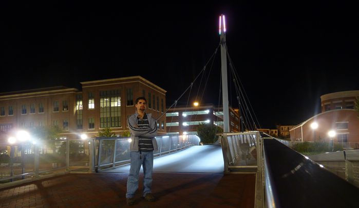 Well, yes that's me...
That's me at a nice scene of lighting, most likely induction posttops, with some MH posttops, some HPS, LEDs under rails on a bridge and of course colored LEDs on the top of the bridge. There was some nice looking MV yardblasters (the nicer more decorative kind) on a building in front of me. There are also metal halide pendent lights after the bridge. Nice view huh? I had the camera auto shutter...although I was with a new friend who is an electrican engineer. He is not into lights but thought was cool. 
Keywords: Lit_Lighting